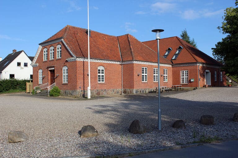 Samlingshuset set ude fra parkeringspladsen, der kan tage ca. 50 biler