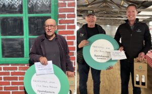 Til venstre Erik Bonne Madsen med hædersbeviset foran scenedekorationen. Til højre scenemester Vagn Thøger Madsen og afdelingsdirektør Claus Lyngbakke fra Sparekassen Danmark.
